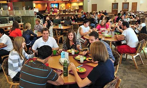 一大群男女学生在校园中心的主餐厅吃午餐